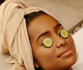 Woman with cucumber facial treatment